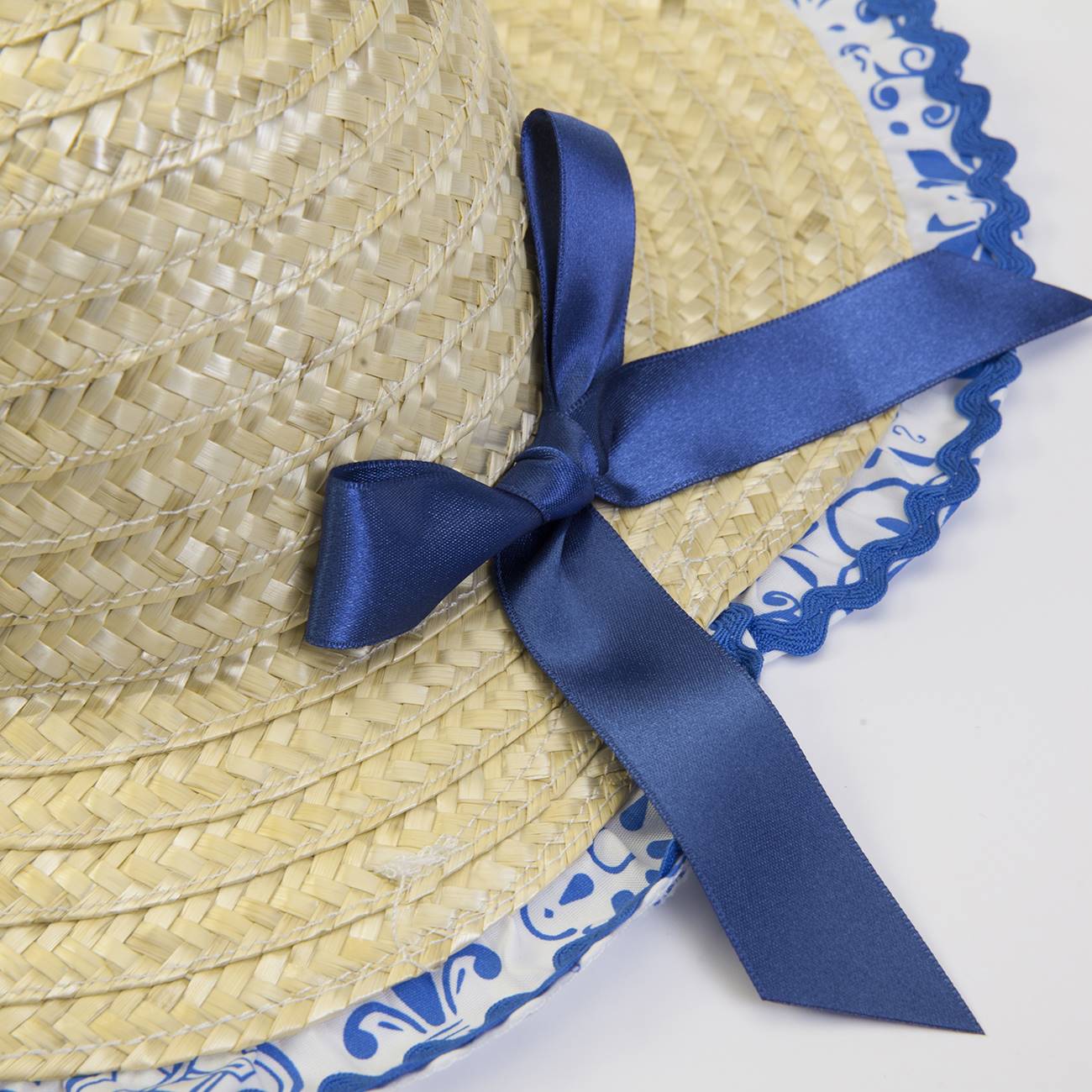 Chapéu de palha bege com fita azul escura e borda azul e branca decorativa