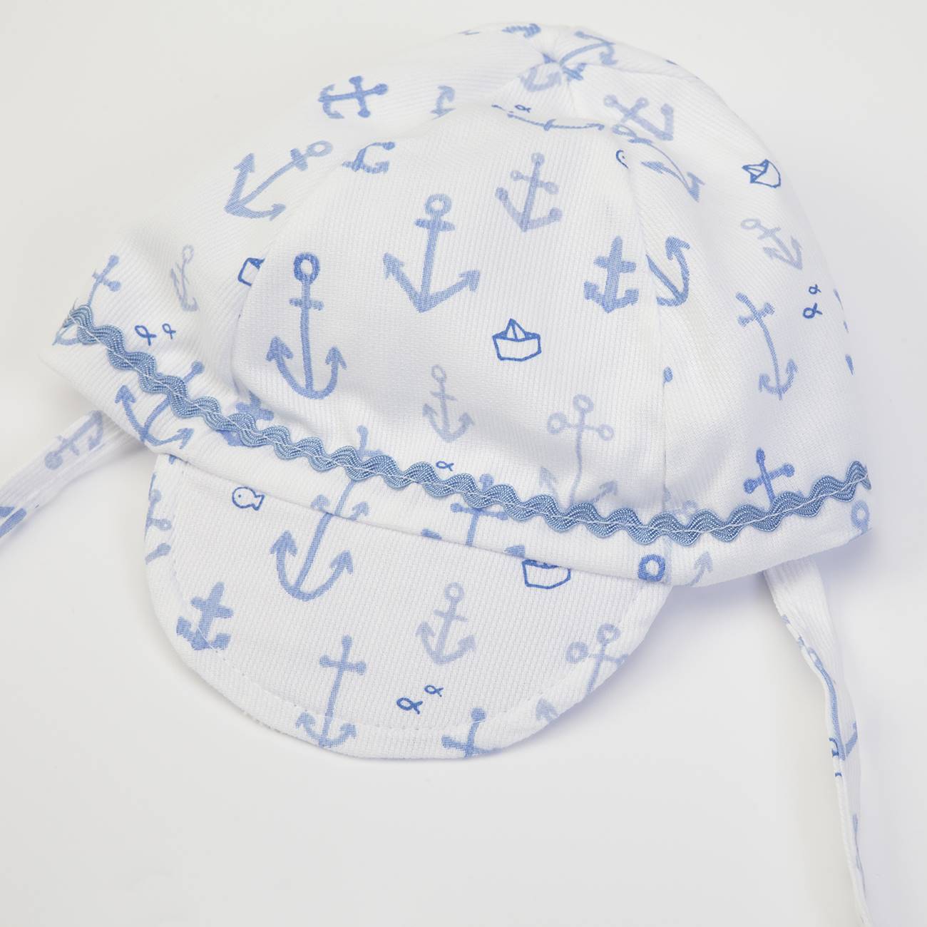 Boné branco com padrão de âncoras azuis e barquinhos, com aba e fita para amarrar
