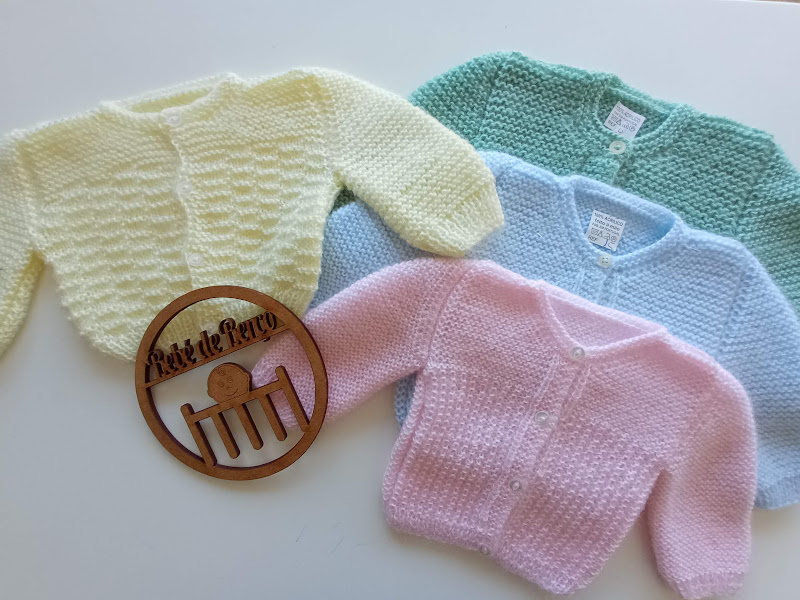 Casacos de malha para bebé em várias cores pastel sobre fundo branco