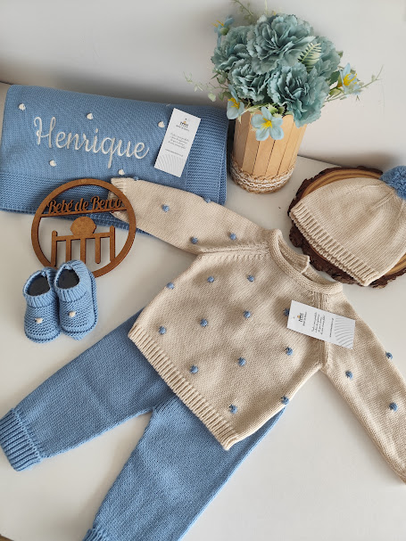 Conjunto de roupa de bebé em malha azul e bege com manta e flores