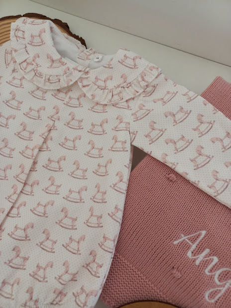 Roupinha de bebé rosa com padrão de cavalinhos de baloiço e manta rosa bordada