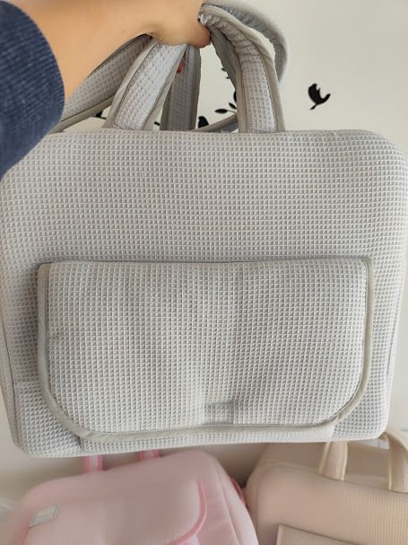 Mala de mão cinzenta clara com bolso frontal e textura de malha quadrada