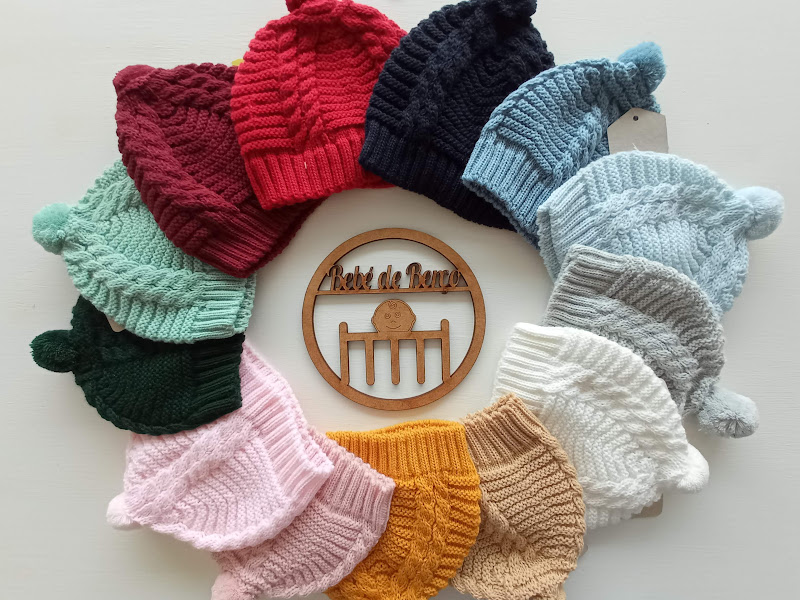 Conjunto de gorros de lã coloridos em círculo com placa de madeira ao centro