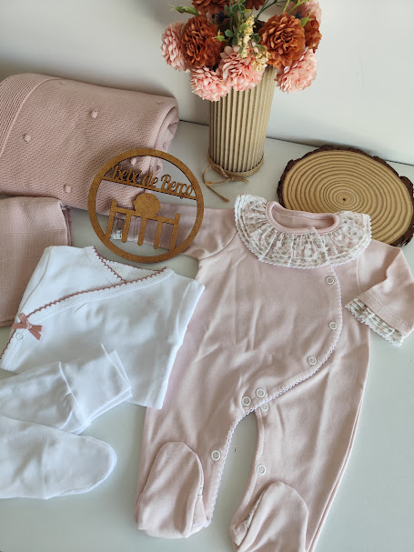 Conjunto de roupa de bebé com macacão rosa, body branco, mantas rosas, flores decorativas e placa de madeira Bébé de Berço