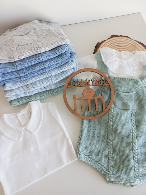 Conjunto de roupa de bebé com body verde, camisola branca e casacos de malha azul e verde empilhados