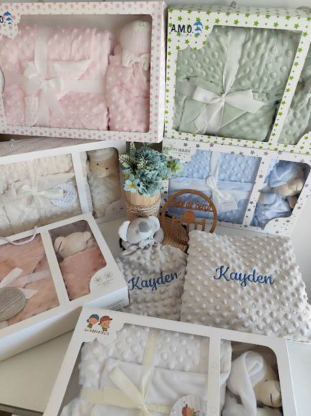 Conjunto de mantas e peluches para bebé em tecido macio com textura de bolinhas e embalagem visível.