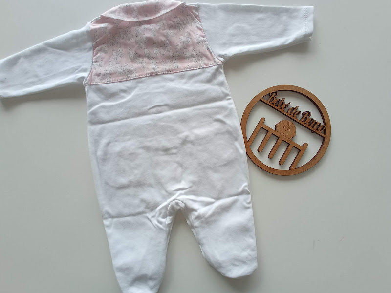 Pijama branco e rosa para bebé com logótipo em madeira ao lado.