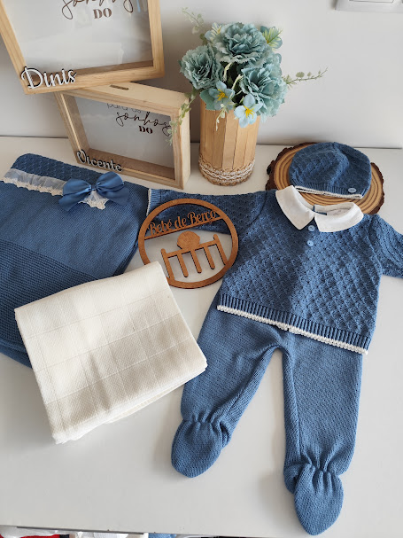 Conjunto roupa bebé azul, manta branca, caixas madeira, vaso flores decorativas