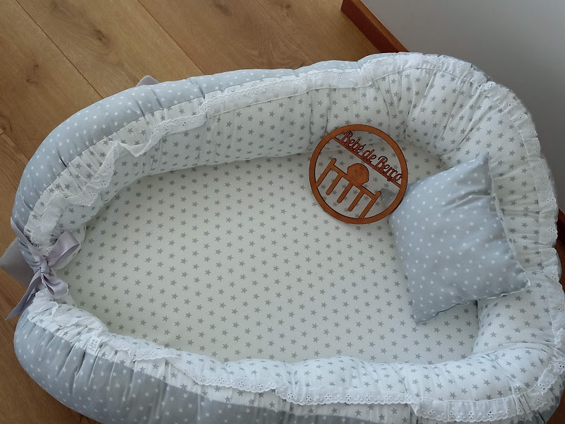 Berço portátil cinza e branco com padrão de estrelas e almofada cinza