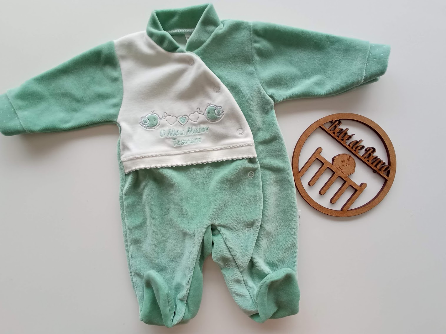 macacão de bebé verde água e branco com bordado e placa redonda de madeira
