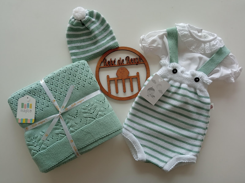 Conjunto de bebé com body branco, jardineira às riscas verde e branca, touca com pompom e manta verde de malha