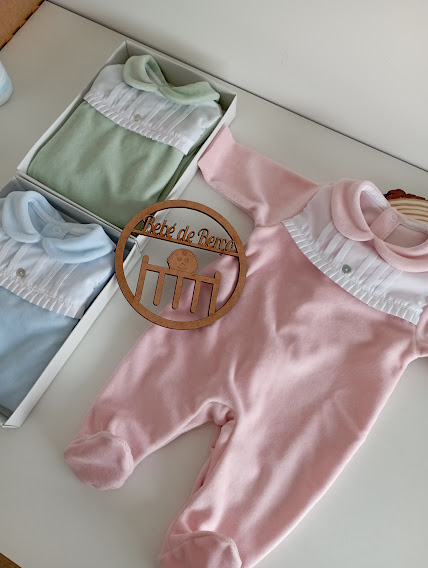 Macacões de bebé coloridos com gola e detalhes brancos em superfície branca