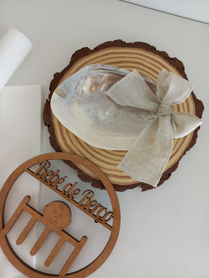 Prato cerâmico branco e bege com base de madeira e laço de tecido, ao lado enfeite de madeira com texto