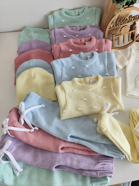 Conjunto de roupa de bebé em várias cores pastel com textura em relevo