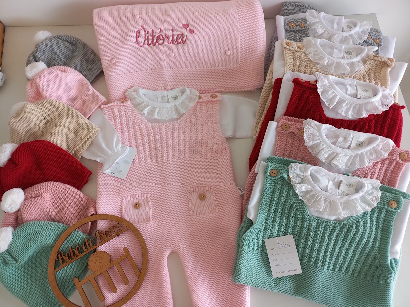 Conjunto de roupa de bebé em tricô colorida com manta bordada VITÓRIA e cabide de madeira.