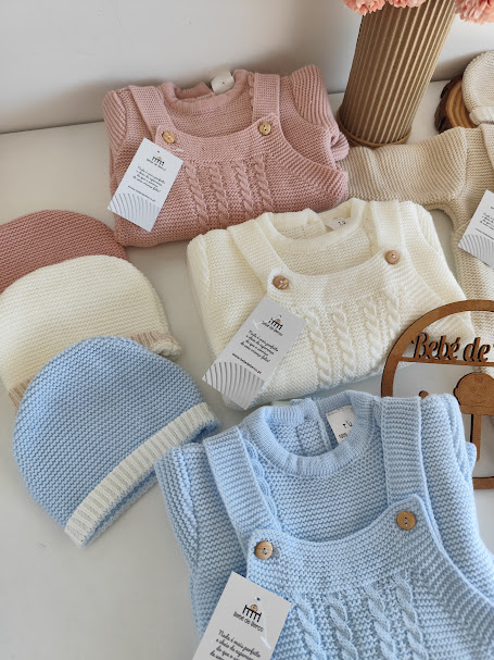 Roupas de bebé de malha em rosa, branco e azul com gorros e etiquetas de marca