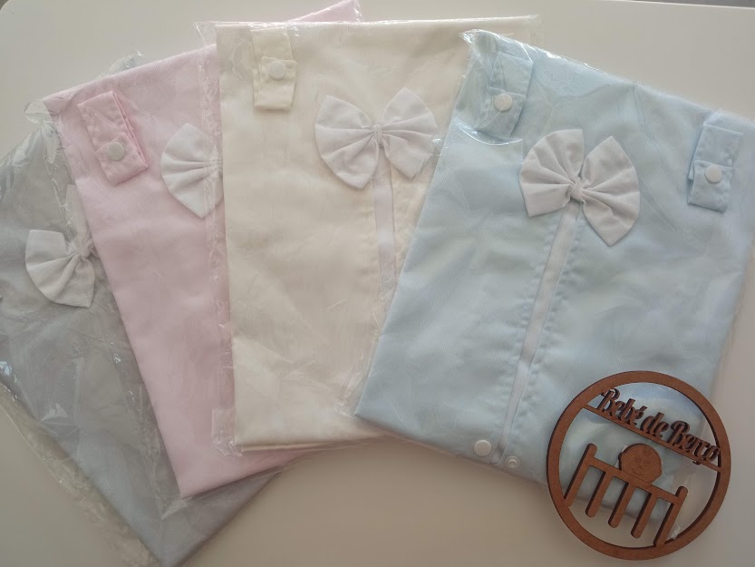 Bodies de bebé de várias cores pastel, cada um com laço, embalados em plástico transparente