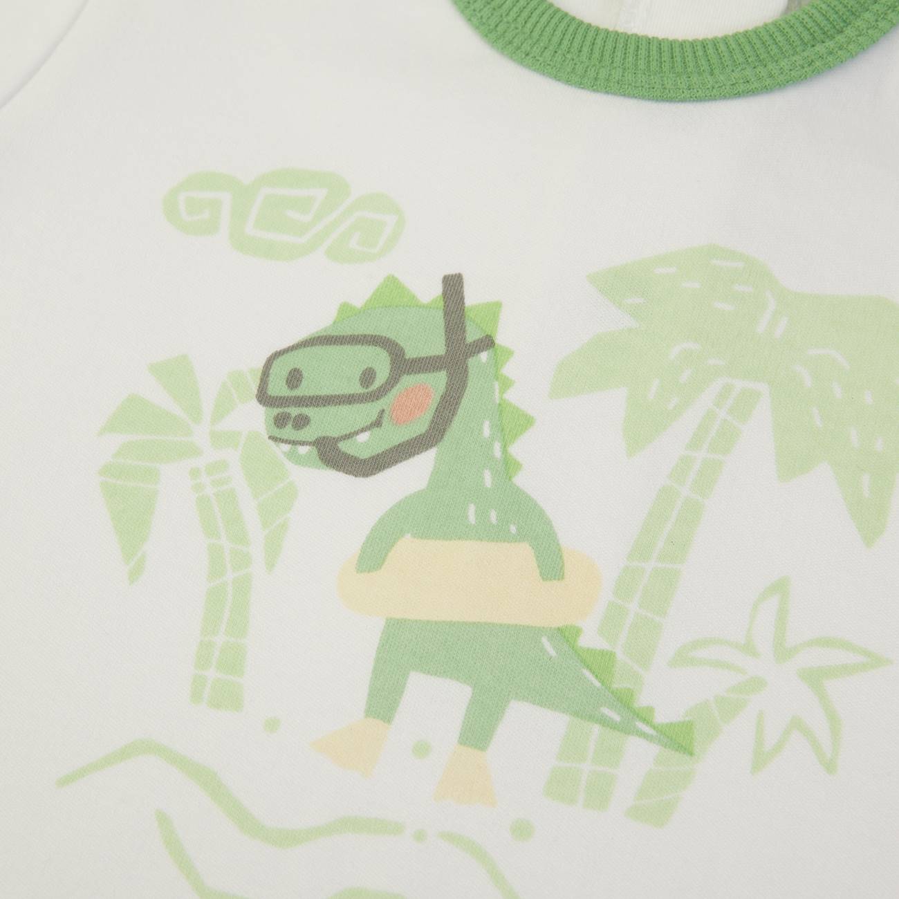 Estampa de dinossauro verde com acessório de mergulho numa peça de roupa branca com gola verde.