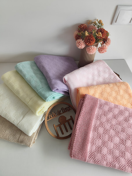 Toalhas coloridas empilhadas com padrões texturizados e um vaso com flores