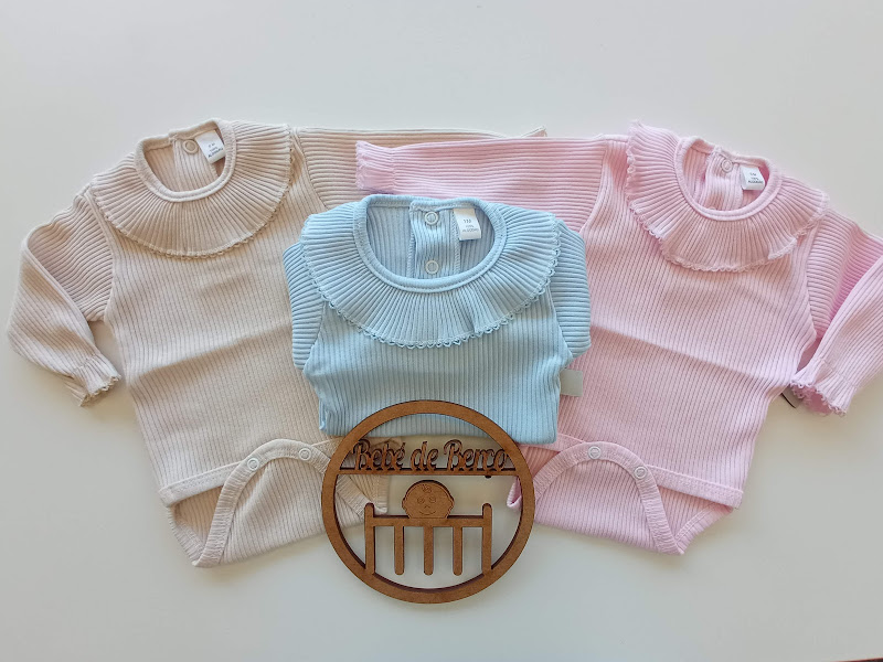 Bodies de bebé em bege, azul claro e rosa com gola franzida e ornamento de madeira