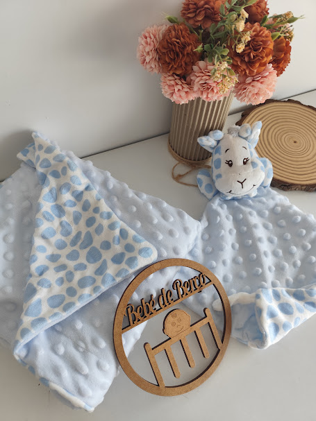 Manta azul claro com cabeça de girafa e flores decorativas ao fundo