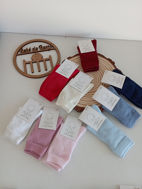 Oito pares de meias infantis coloridas em mesa branca com placa de madeira com texto