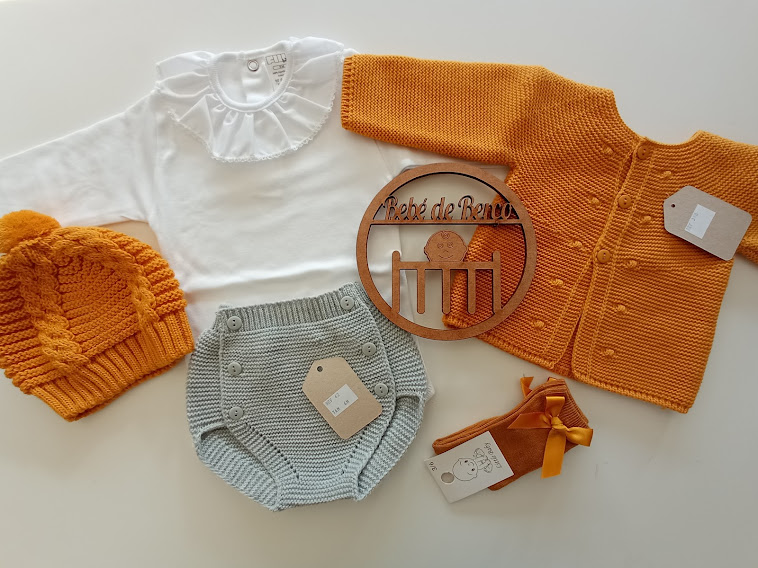 Conjunto de roupa de bebé com camisola branca, casaco e touca laranja, cuecas cinzas e sapatos laranja