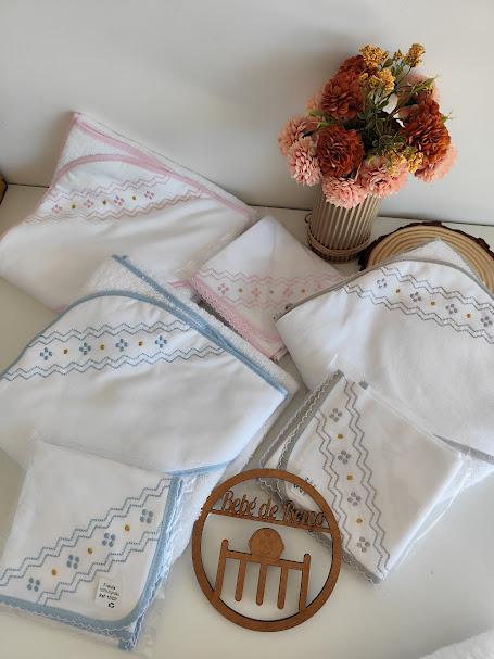 Toalhas de bebé brancas com bordados coloridos e vaso com flores artificiais