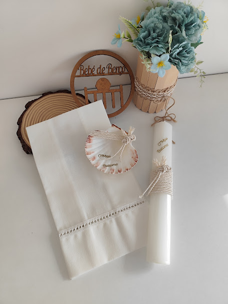 Conjunto decorativo com vela, toalha branca, concha, flores azuis e base de madeira