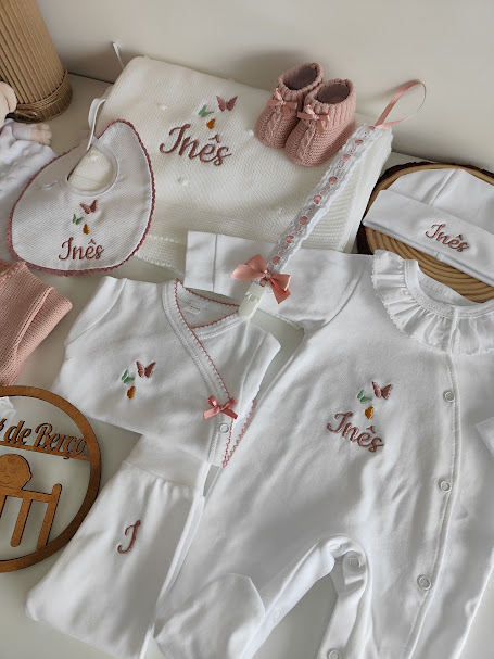 Roupa e acessórios de bebé com bordados e nome 'Inês'