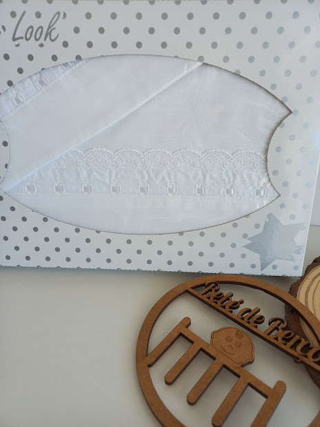 Toalha branca com renda em embalagem pontilhada e decoração de madeira com texto