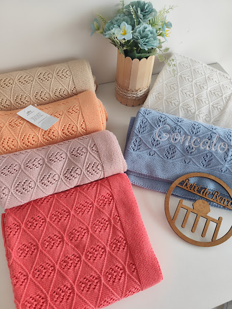 Cobertores em algodão coloridos com padrão geométrico e vaso de flores