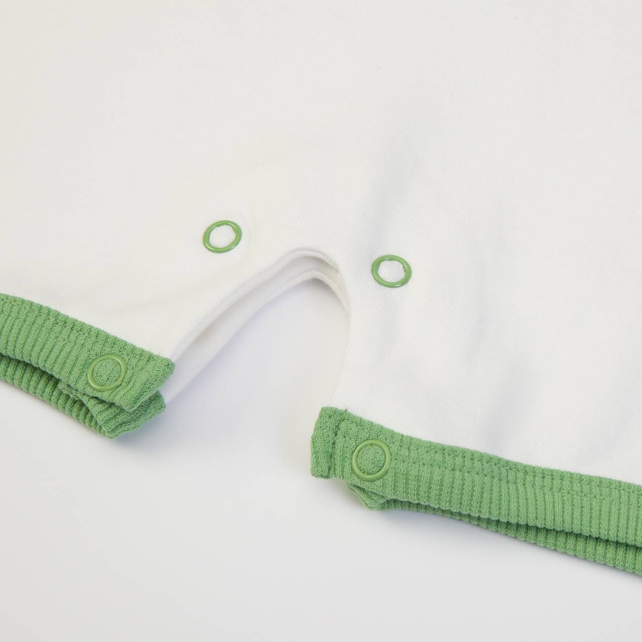 Peça de roupa branca com acabamento verde e botões de pressão