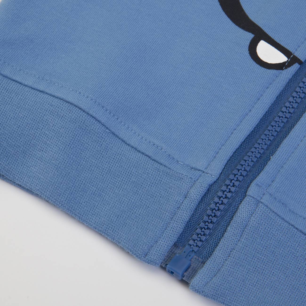 Casaco azul claro com fecho de correr azul escuro e detalhe de olho impresso