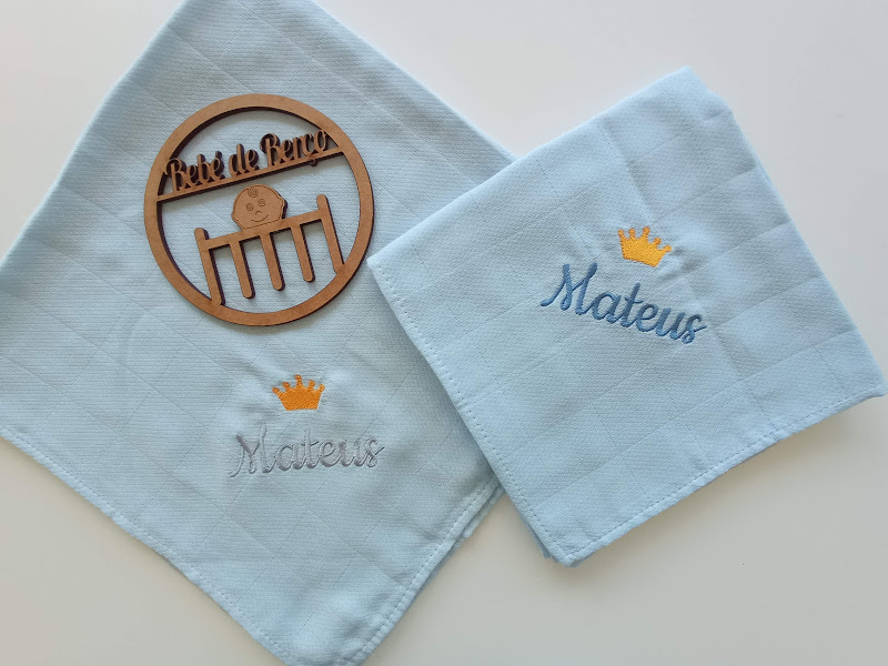 Dois panos de boca com nomes bordados e uma placa decorativa de madeira