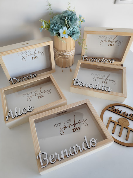 Caixas de madeira com nomes e texto para os sonhos DO, com vaso de flores azuis e brancas ao centro
