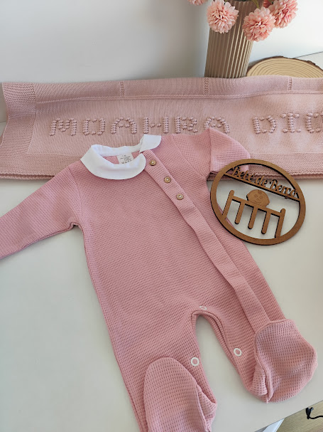 Macacão rosa de malha com gola branca e manta rosa com texto ao fundo