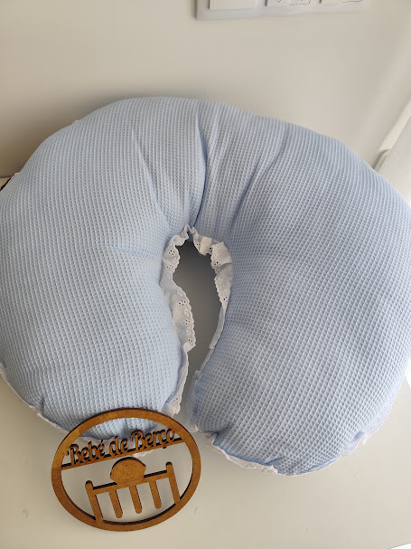 Almofada azul clara com textura quadriculada e rendas branca, placa de madeira com texto Bebé de Berço