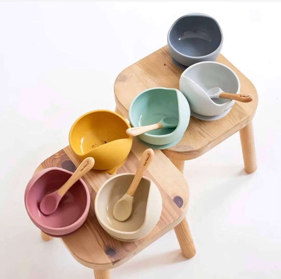 Seis tigelas cerâmicas coloridas com colheres de madeira em mesas de madeira clara