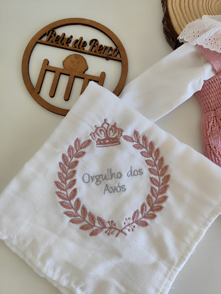 Fralda branca bordada com texto 'Orgulho dos Avós' e placa decorativa de madeira