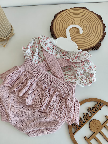 Conjunto de roupa de bebé rosa e branco com padrão floral, calças de malha e cabide branco