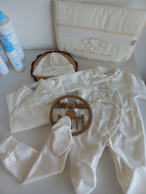 Conjunto de roupa de bebé cru com bordados bege e embalagens de produtos de cuidado