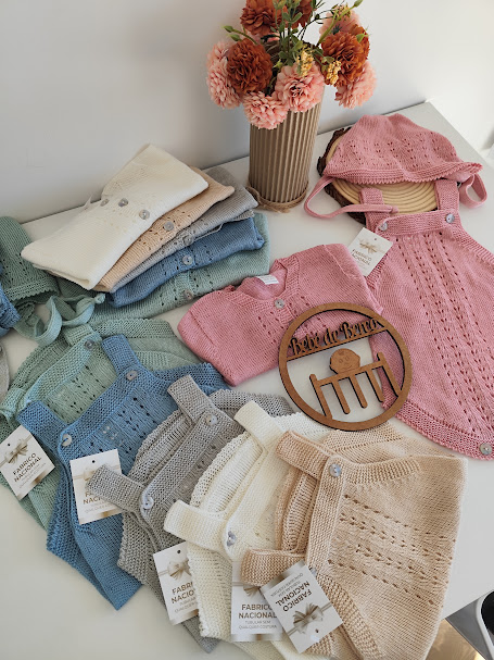 Roupas de bebé em malha coloridas e etiquetas no tecido num mostrador branco