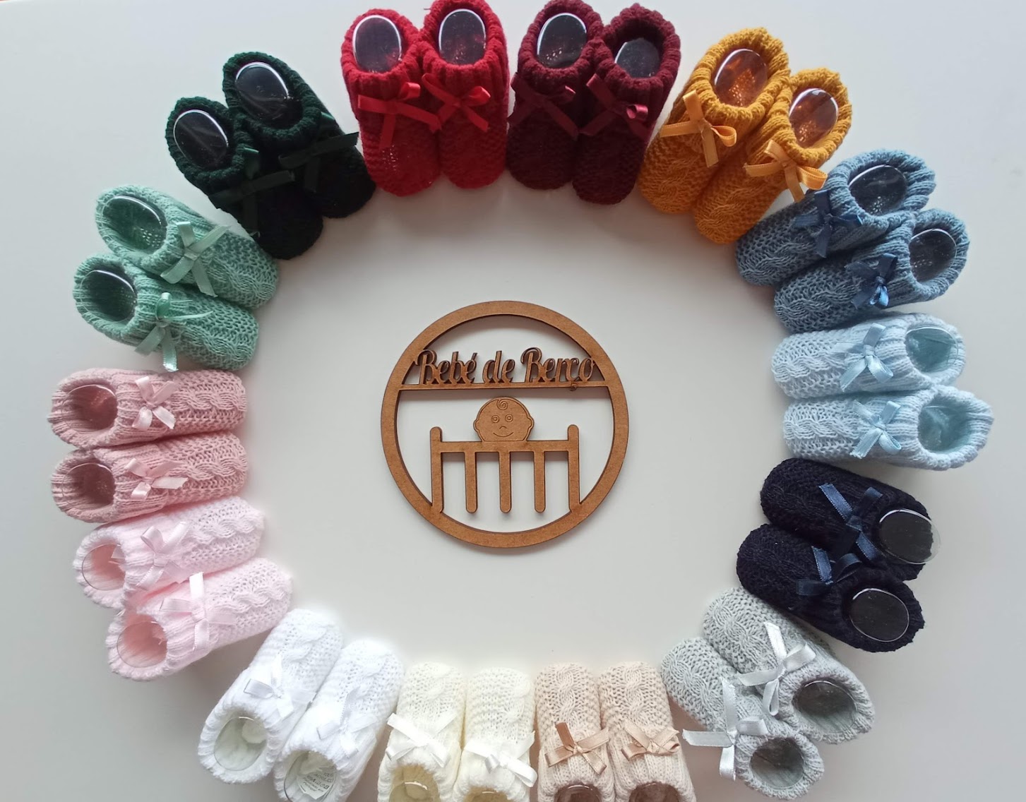 Sapatinhos de bebé em tricô coloridos dispostos em círculo