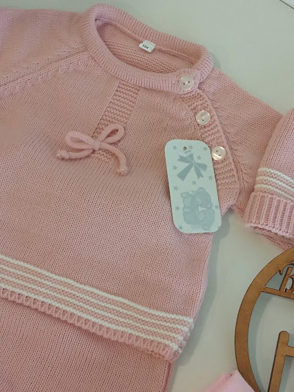 Conjunto de roupa de bebé em malha rosa com botões e detalhes brancos.