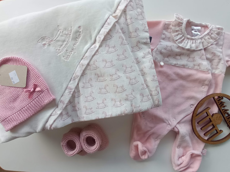 Conjunto de roupa de bebé rosa e branca com saco de dormir, macacão, gorro e botinhas