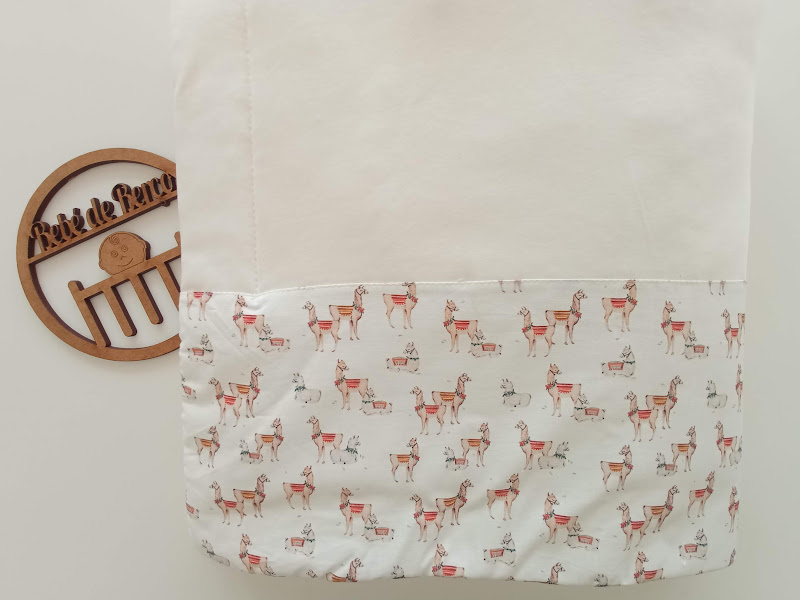 Fralda branca com padrão de camelos castanhos e detalhes vermelhos