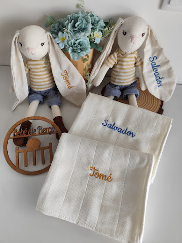 Bonecos de coelho de tecido com roupa às riscas e panos de tecido branco bordados com nomes