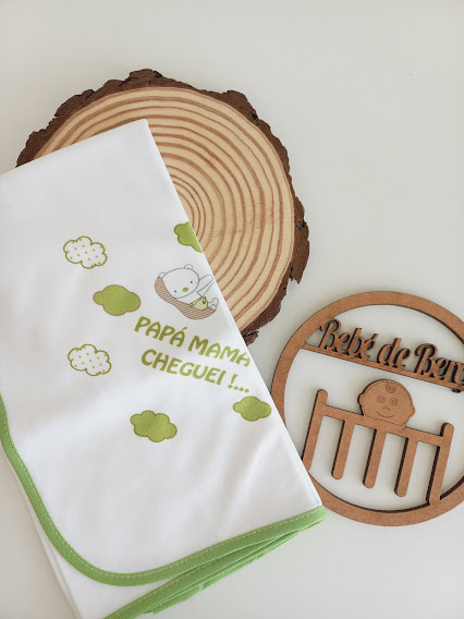 Fralda branca com bordas verdes e estampa de ursinho e nuvens verdes com texto 'PAPÁ MAMÃ CHEGUEI!...' e ornamento de madeira 'Bebé de Banho'
