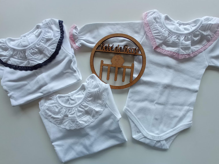 Três bodies brancos para bebé com gola rendada e decoração de madeira com texto